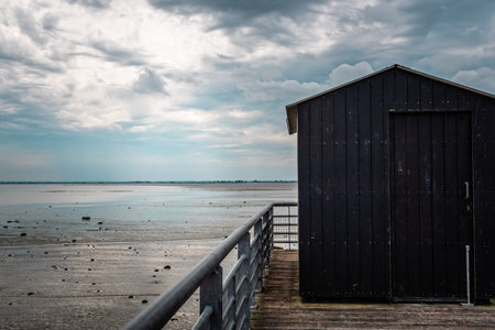 A pier on a sandy low tide beach under the cloudy blue sky on the coast in Cancale,Brittany, Franceの写真素材