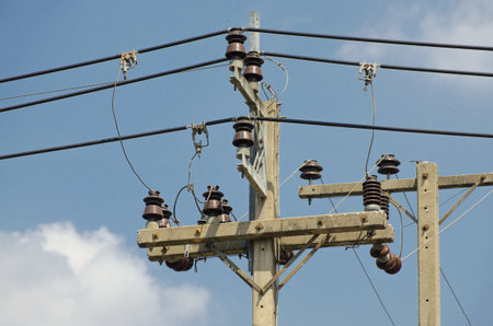 the electrical insulators set with transmission lines on background of sky and clouds