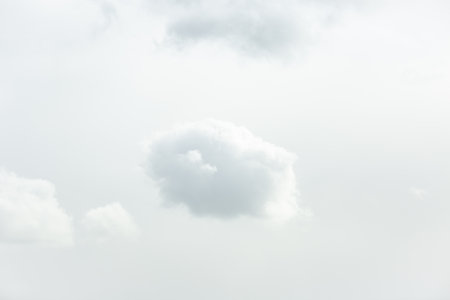 Single fluffy cumulus cloud formation solitary drifting in cloud filled frame.