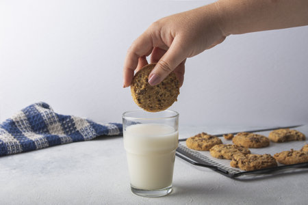 A woman's hand dipping a peanut butter cookie in a fresh milkの写真素材