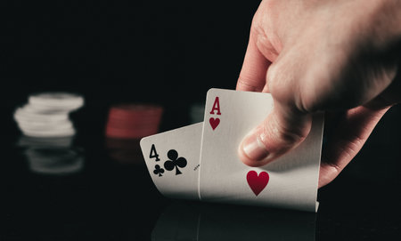 A person subtly raising poker cards on black background
