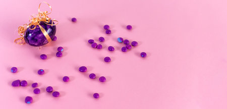 A close-up shot of a violet easter egg and candies on a pink background.の写真素材