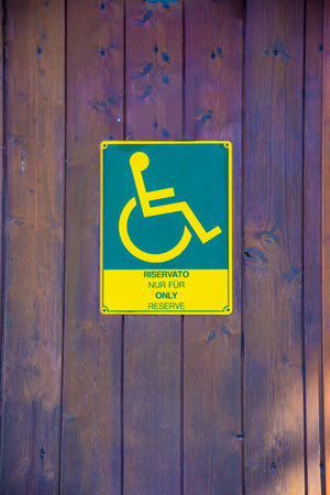 A green-yellow plastic sign for the toilet of a wheelchair user with the indication in several languages that it is for wheelchair users onlyの写真素材