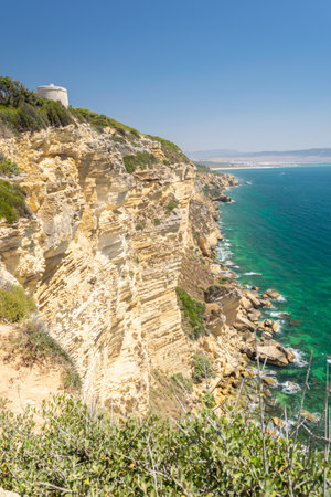 A vertical shot of the Tower of Tajo on cliffs surrounded by the sea in Spainの写真素材