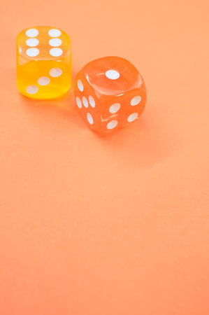 A vertical shot of yellow and red dice on a pastel orange backgroundの写真素材
