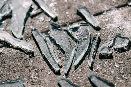 A closeup shot of broken glasses scattered on the concrete surfaceの写真素材