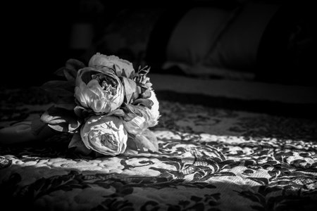A grayscale shot of a bouquet on the bedの写真素材