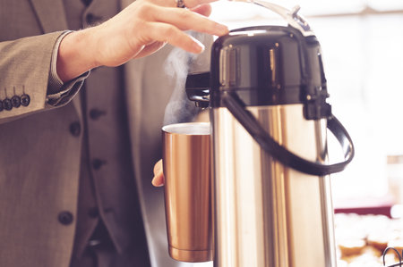 A view of a man in tuxedo getting hot water on a  in a conferenceの写真素材