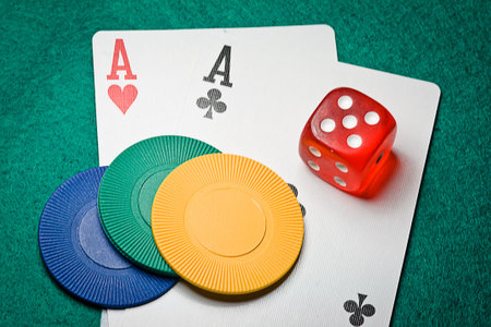 A pair of aces with dice and poker chips on a green table in casino
