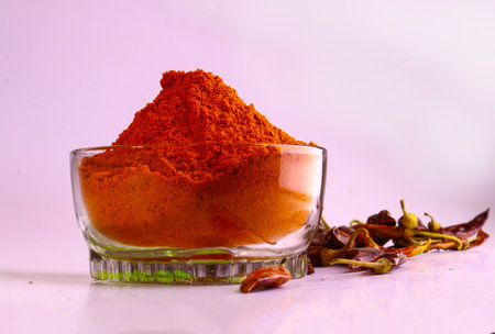 A bowl of dried chilly pepper powder and dry red chilly peppers isolated in the vibrant background