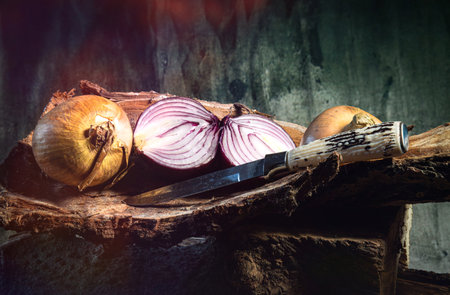 A closeup of sliced onions on a wooden surface with a sharp knifeの写真素材