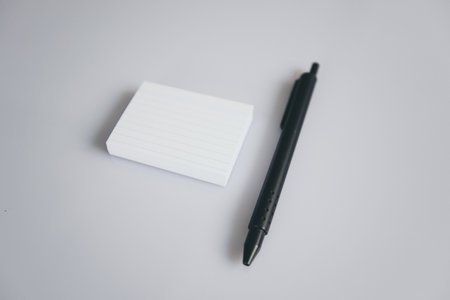 A closeup shot of a black pen and a pad of small paper isolated on white background with copyspaceの写真素材