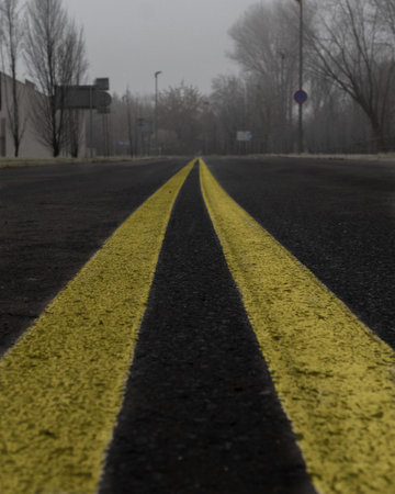 A vertical shot of double yellow lines on asphalt roadの写真素材