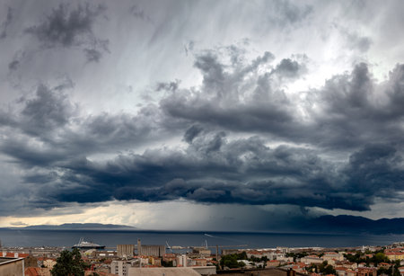A scenic shot of cloudscape with beautiful sunrays across the ocean  and costal villageの写真素材