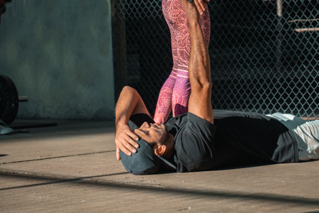 very tired athlete after a fitness routine, asking his partner for help to get up, after cross fit...
