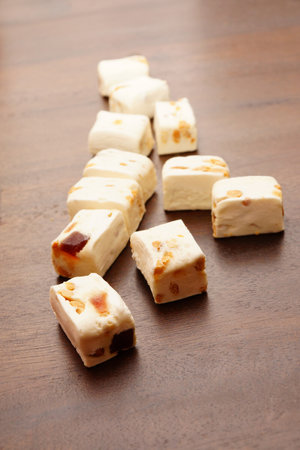 A vertical shot of soft nougat with peanuts and fruits in a wooden tableの写真素材