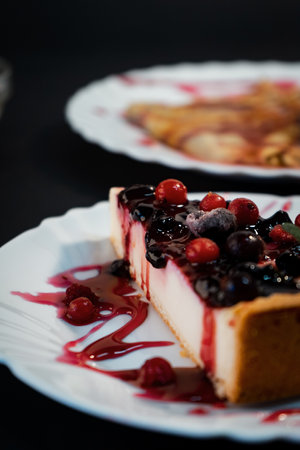 A vertical shot of a delicious cheesecake with berries and syrupの写真素材