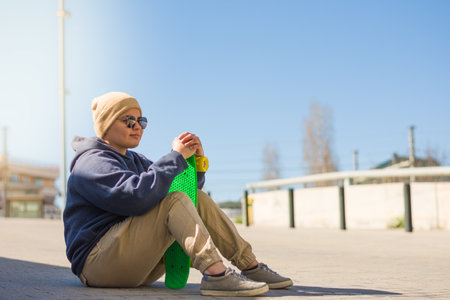 A Spanish female skateboarder resting outdoorsの写真素材