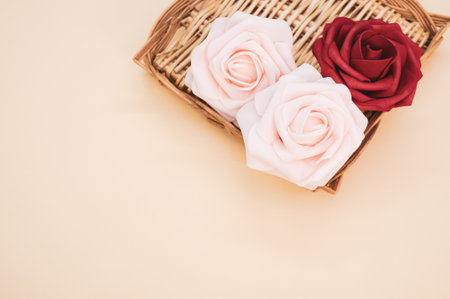 A wicker tray with red and pink roses on a light background with space for textの写真素材