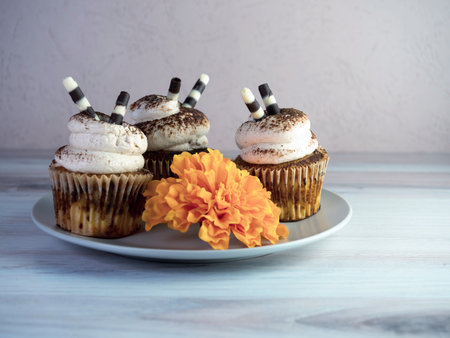 A closeup of buttercream flavored cupcakes with flower on the tableの写真素材