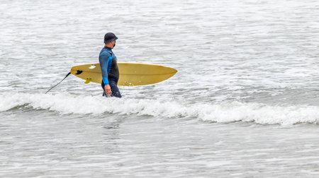 A surfer holding a yellow board in the waterの写真素材