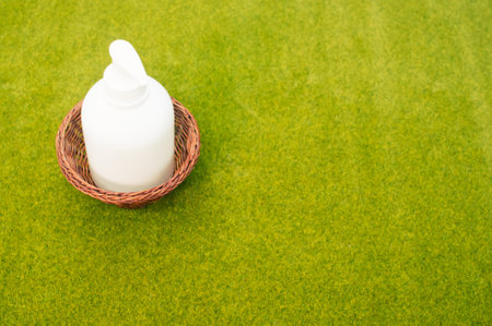 A white pump bottle dispenser on a wooden basket on a green grass surfaceの写真素材