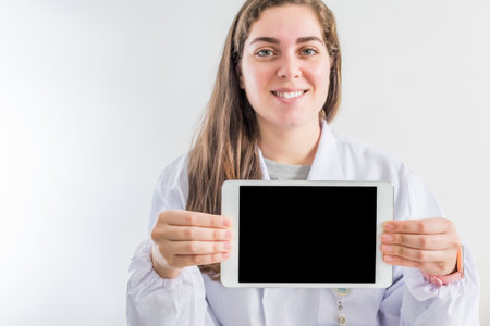 A young professional female doctor sitting in her consulting room showing a blank screen of a tablet