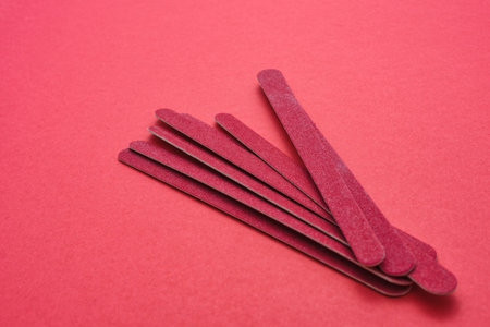 A beautiful shot of red sandpapers made for nail treatment on a light red surfaceの写真素材