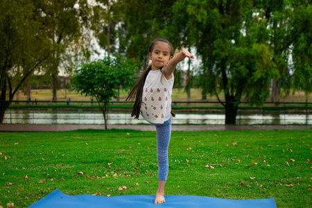 A closeup shot of a cute Latin girl practicing yoga in a parkの写真素材
