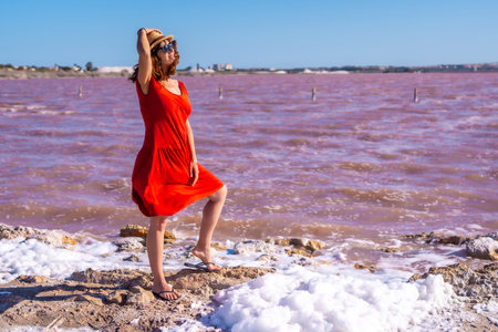A girl with red dress and straw hat in the pink lagoon of Torrevieja, Alicante. Community of Valencia. Spain, holidays in the Mediterraneanの写真素材