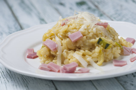 A close-up shot of a plate of rice with zucchini, cheese, and hamの写真素材