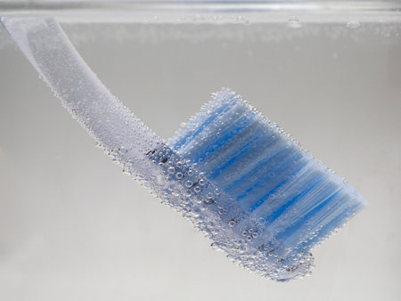A closeup shot of a toothbrush with bubbles on it inside water