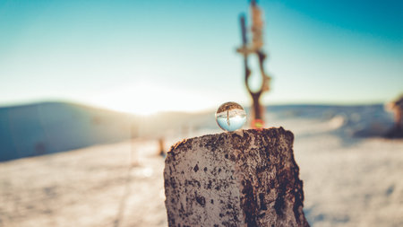 A selective focus shot of a small glass globe on a trunk with a desert in the backgroundの写真素材