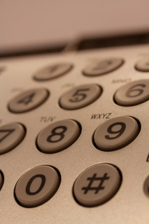 A vertical shot of the buttons of a white telephone with numbers and symbolsの写真素材