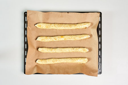 A top view of raw dough rolls with a shredded pumpkin on a white surface