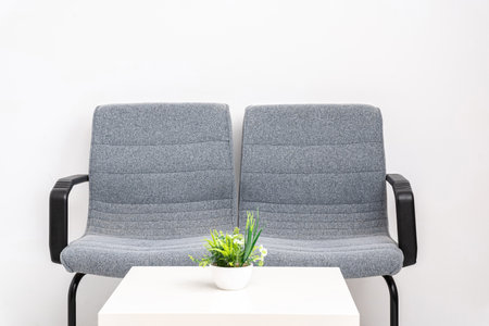 The two gray chairs on a waiting room with a white table isolated on white background with copy...