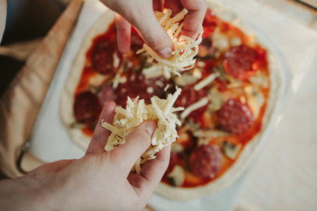 The process of making a homemade pizza with salami and cheeseの写真素材