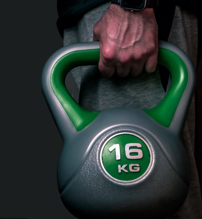 Kettlebell on a black background . The fist of an athlete grasping kettlebell . Close-up of a muscular hand holding a kettlebell.の写真素材