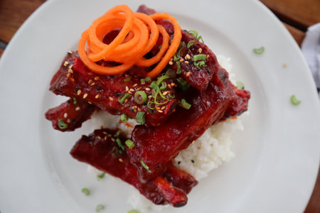 A Closeup of spare ribs dish on a bed of rice with chives and shaved carrot garnish rosemary garnishの写真素材