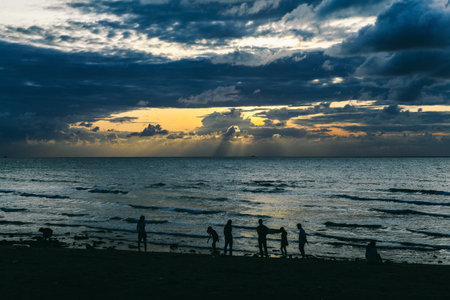 A group of people enjoying scenic sunset at the beachの写真素材