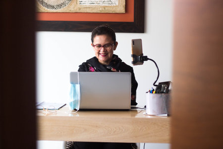 A smiling boy with a computer at home