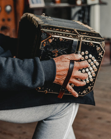 A closeup shot of an old man's hand playing Bandoneon musical instrumentの写真素材