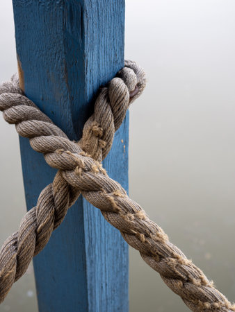 A vertical shot of a rope tied around a blue wooden columnの写真素材