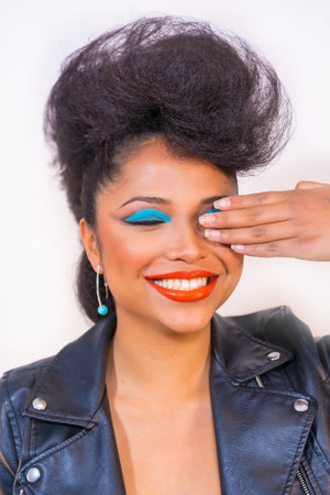A happy smiling gorgeous hipster girl with bright makeup and cool hairstyle closing one eye with her...