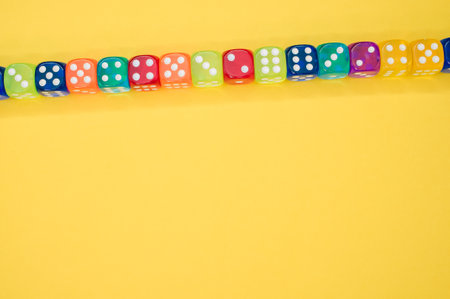 Colorful dice in a row isolated on a yellow backgroundの写真素材