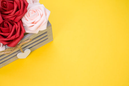 Beautiful red and white roses in a box isolated on a yellow backgroundの写真素材