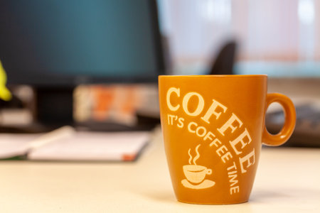 A brown coffee mug with writings about coffee on the tableの写真素材