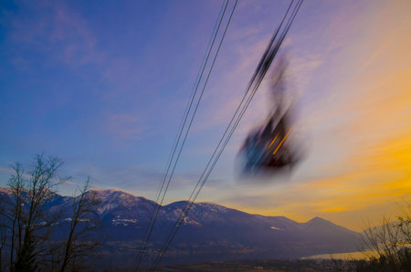 Cableway in Long Exposure over an Alpine Lake Maggiore with Snow-capped Mountain in Dusk in Locarno, Switzerland.の写真素材