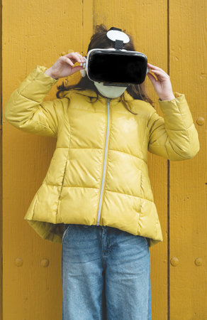 The picture shows an American shot of a Caucasian girl wearing a coronavirus mask with virtual reality gogglesの写真素材