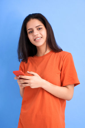 A Latin woman with phone in hands smiling